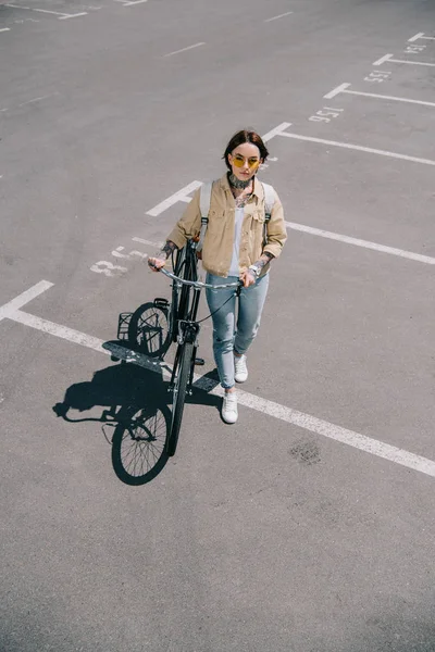 Высокий угол обзора стильной женщины с велосипедом на парковке — стоковое фото