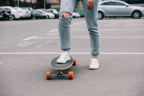 Teilansicht einer stylisch tätowierten Skateboarderin auf einem Parkplatz — Stockfoto