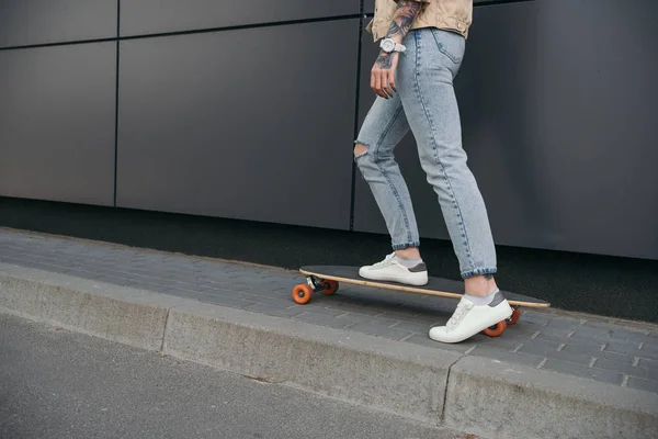 Abgeschnittenes Bild tätowierter Skateboarderin auf der Straße — Stockfoto