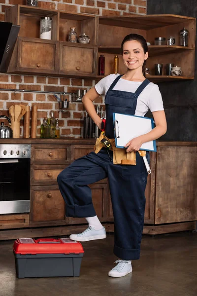Bela jovem reparadora com ferramentas e prancheta na cozinha — Fotografia de Stock