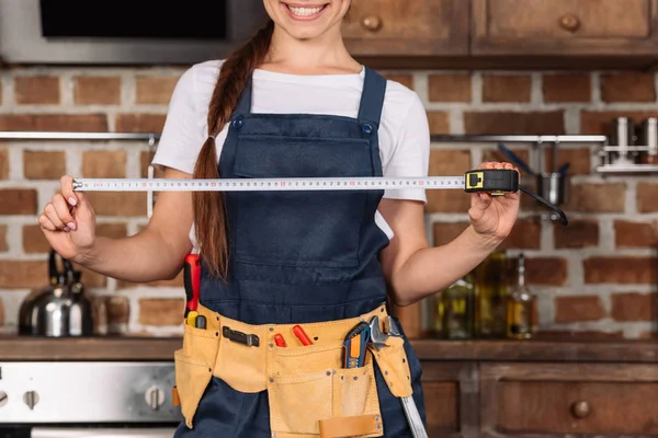 Cropped shot of smiling young repairwoman with measuring tape — Stock Photo