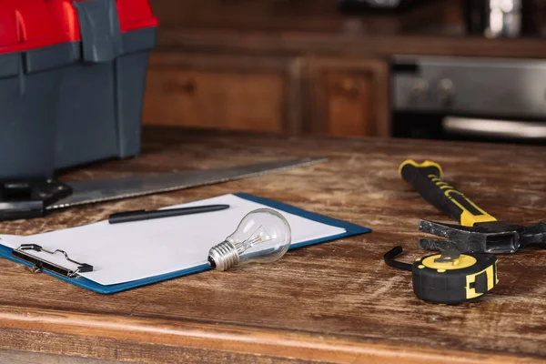 Close-up shot of blank clipboard with tools on wooden table — Stock Photo