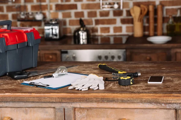 Close-up shot of blank clipboard with various tools on wooden table — Stock Photo