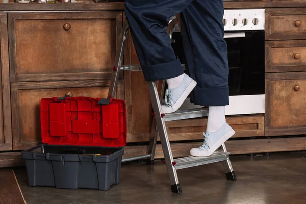 Plan recadré de réparatrice debout sur escabeau à la cuisine — Photo de stock