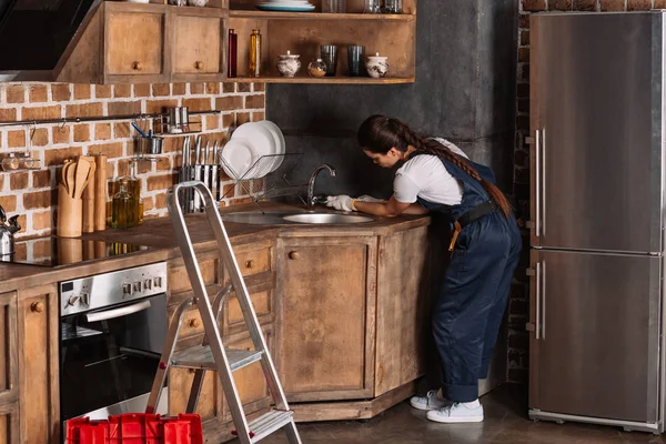 Jeune plombier femelle avec clé à molette réparer évier de cuisine — Photo de stock