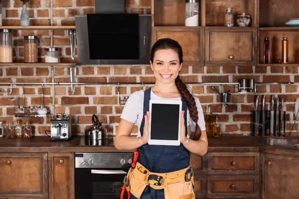 Heureux jeune réparatrice debout à la cuisine avec tablette vierge — Photo de stock