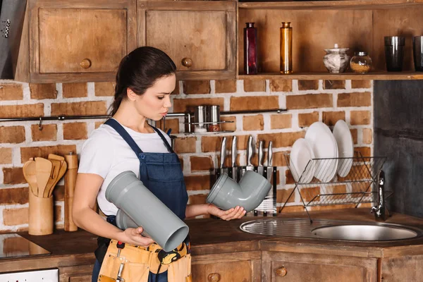 Atraente jovem encanador em geral com tubos de plástico na cozinha — Fotografia de Stock