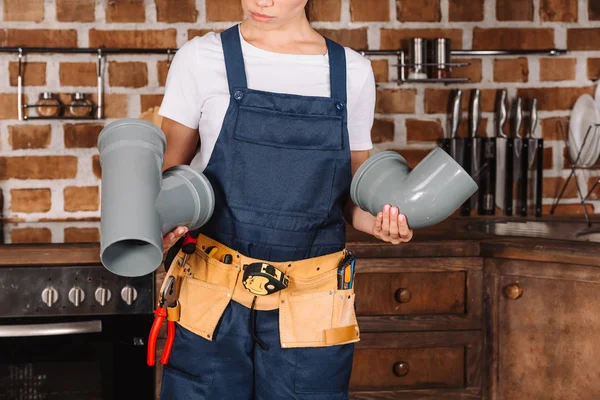 Cropped shot of female plumber with plastic pipes at kitchen — Stock Photo