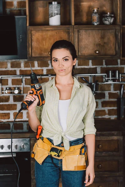 Attraktive junge Reparaturfrau mit Bohrmaschine und Blick in die Kamera — Stockfoto