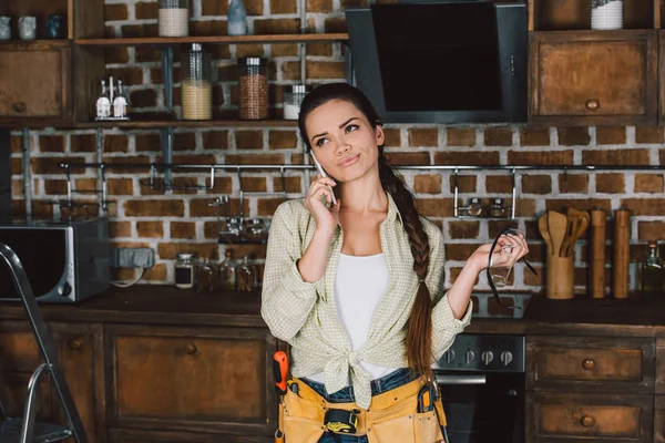 Jeune réparatrice expressive parlant par téléphone et regardant la cuisine — Photo de stock