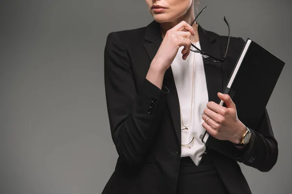 Abgeschnittenes Bild einer Geschäftsfrau mit Brille und Lehrbuch isoliert auf grauem Hintergrund — Stockfoto