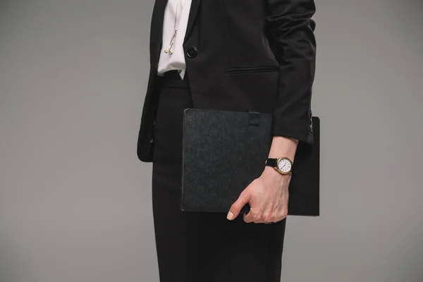 Imagen recortada de mujer de negocios con reloj de pulsera sosteniendo libro de texto aislado sobre fondo gris - foto de stock