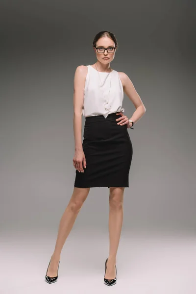 Attraente donna d'affari in occhiali posa su sfondo grigio — Foto stock