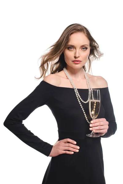 Mulher elegante confiante em vestido preto segurando copo de champanhe isolado no fundo branco — Fotografia de Stock