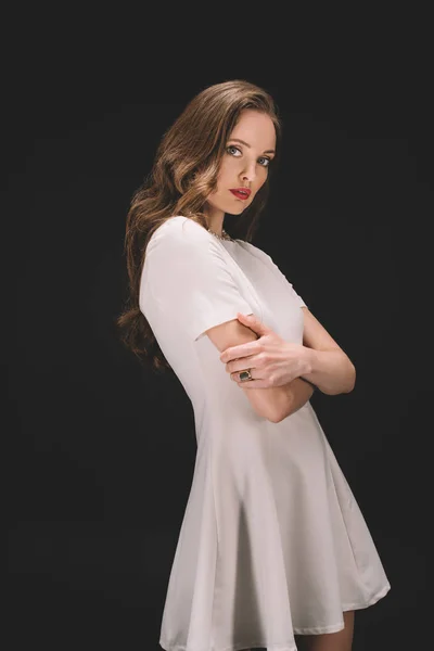 Attractive female model with crossed arms looking at camera isolated on black background — Stock Photo