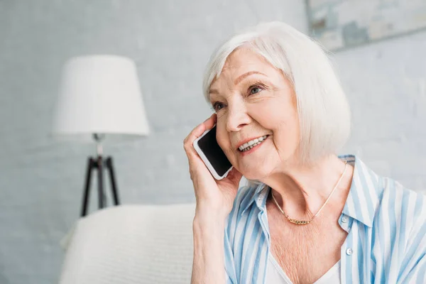 Retrato de mulher sênior sorrindo falando no smartphone em casa — Fotografia de Stock