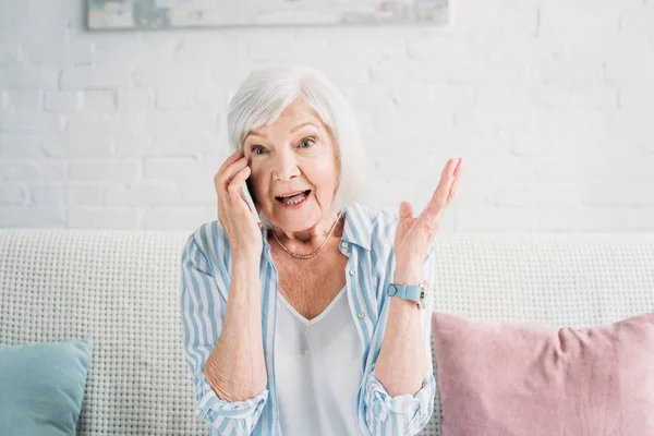Retrato de mujer mayor emocional hablando en el teléfono inteligente en casa - foto de stock