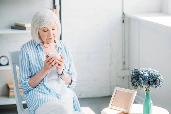 Portrait de femme âgée avec tasse de café aromatique dans les mains à la maison — Photo de stock