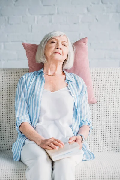 Portrait of senior woman with book sleeping on sofa at home — Stock Photo