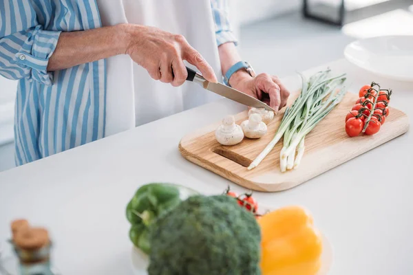 Colpo ritagliato di funghi taglio signora anziana durante la cottura cena al bancone in cucina — Foto stock