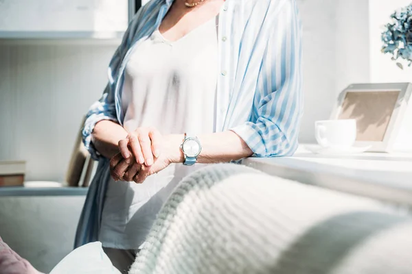 Cropped shot of senior woman leaning on sofa at home — Stock Photo