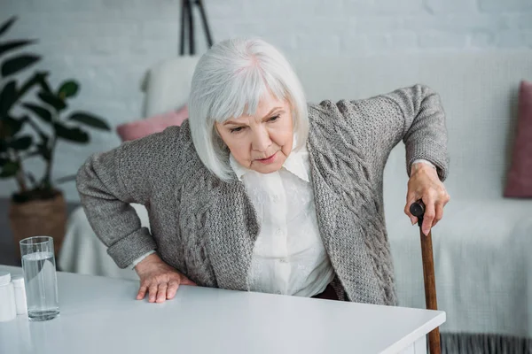 Portrait de femme aux cheveux gris avec bâton de marche essayant de se lever à la maison — Photo de stock