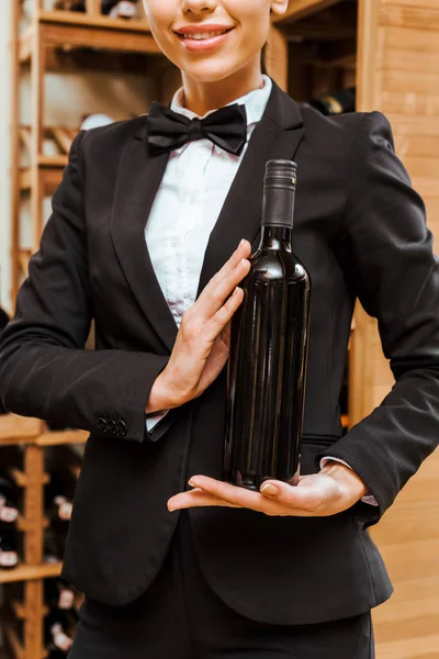 Cropped shot of female wine steward holding bottle at wine store — Stock Photo