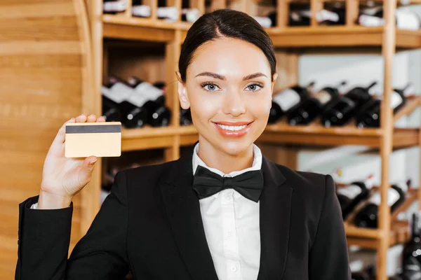 Beautiful female wine steward with golden credit card at wine store — Stock Photo