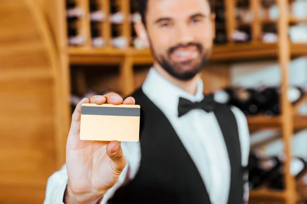 Messa a fuoco selettiva colpo di giovane steward di vino in possesso di carta d'oro in enoteca — Foto stock