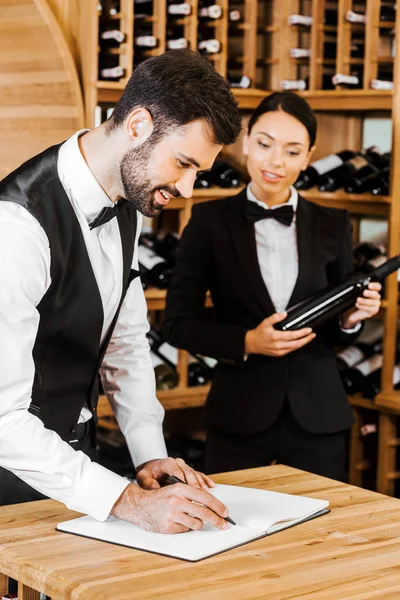 Couple of wine stewards doing stocktaking of wine at store — Stock Photo