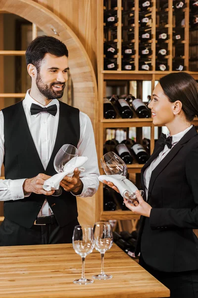 Couple of wine stewards wiping glasses and chatting at wine store — Stock Photo