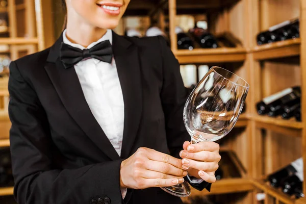 Cropped shot of female wine steward with clean glass at wine store — Stock Photo