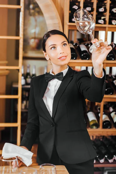 Schöne weibliche Wein-Stewardess überprüft klares Glas im Weinladen — Stockfoto