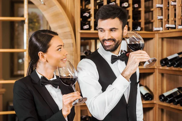 Par de administradores de vinos felices haciendo degustación juntos y charlando en la tienda de vinos - foto de stock