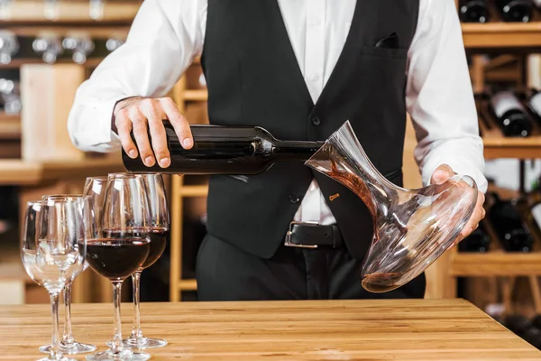 Plan recadré de steward du vin versant du vin dans la carafe au magasin de vin — Photo de stock