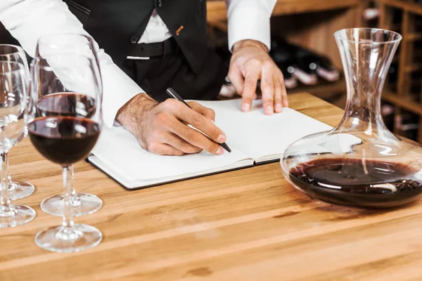 Colpo ritagliato di steward di vino prendere appunti in enoteca — Foto stock