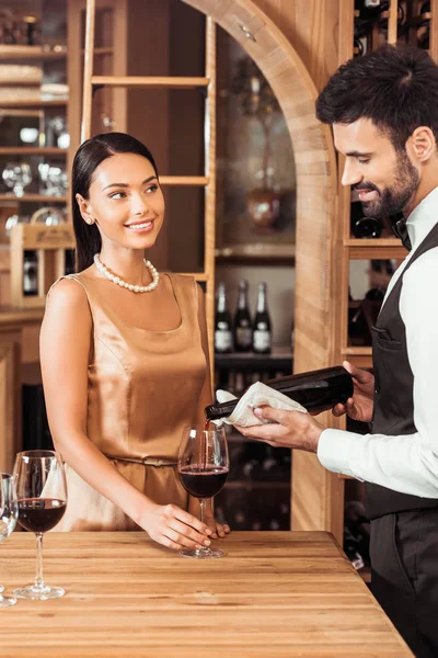 Steward de vin versant du vin pour jeune femme attrayante au magasin de vin — Photo de stock