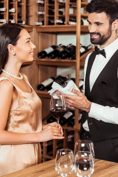 Steward che mostra bottiglia di vino di lusso al cliente femminile in enoteca — Foto stock