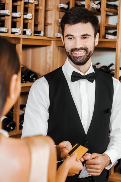 Mayordomo de vino tomando tarjeta de crédito de oro de cliente femenino en tienda de vino - foto de stock