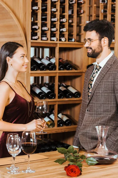 Feliz pareja elegante charlando en el almacenamiento de vino - foto de stock