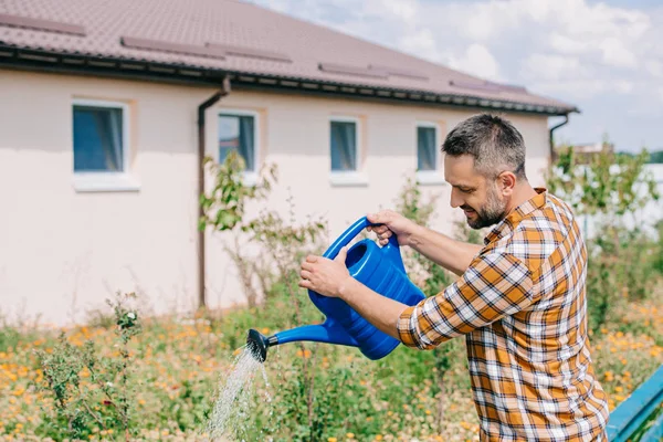 Schöner Bauer mittleren Alters gießt Pflanzen im Garten — Stockfoto