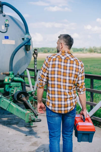 Vue arrière de la boîte à outils de l'exploitation agricole d'âge moyen et examen du véhicule agricole — Photo de stock