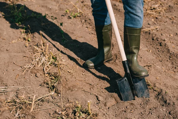 Erschossener Bauer in Gummistiefeln arbeitet mit Schaufel auf Feld — Stockfoto