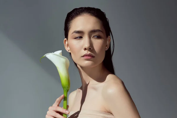 Attractive naked asian girl with calla flower, isolated on grey — Stock Photo