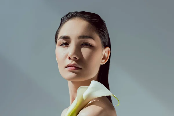 Attraktive zarte asiatische Frau mit Calla-Blume, isoliert auf grau — Stockfoto