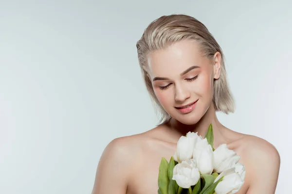 Porträt eines glücklichen nackten Mädchens, das mit Tulpenblumen posiert, isoliert auf grau — Stockfoto