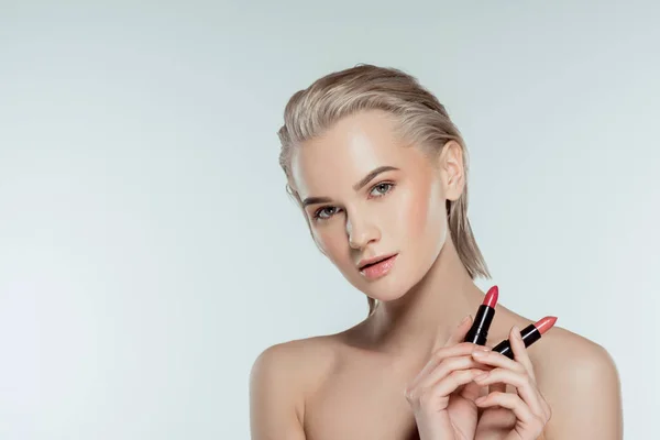 Beautiful woman holding lipsticks, isolated on grey — Stock Photo