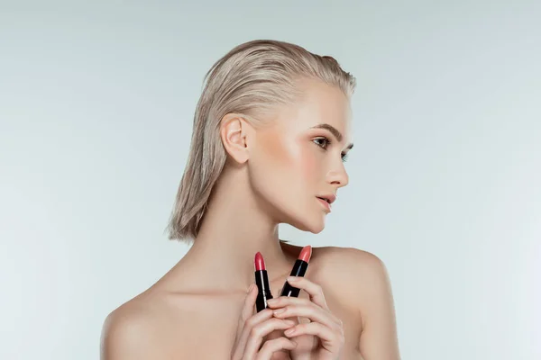 Schöne blonde Frau mit Lippenstiften, isoliert auf grau — Stockfoto
