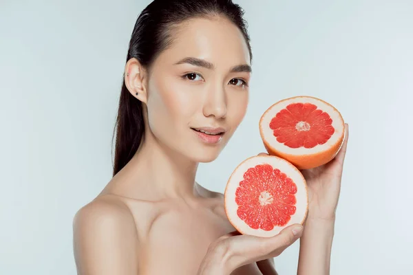 Asiatique fille posant avec pamplemousse moitiés, isolé sur gris, naturel beauté — Photo de stock