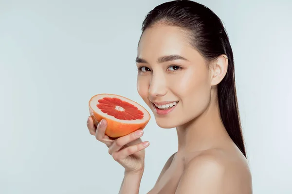 Sonriente asiático chica holding pomelo, aislado en gris - foto de stock